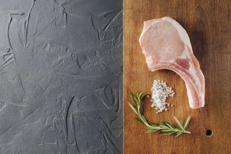 Raw steak is prepared for grilled cooking with baking and salt on a wooden background. Empty space for writing text view from above. Top viewの写真素材