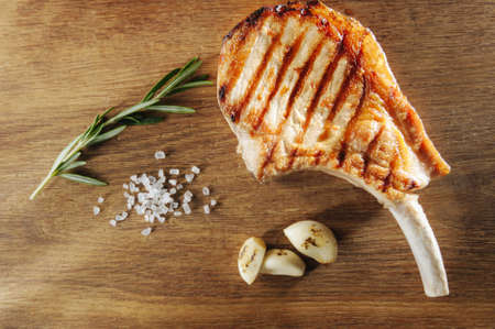cooked steak on the bone with salt and garlic on a wooden board, view from above, top viewの写真素材