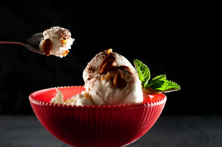 spoon with ice cream on a black background, ice cream summer mood cool. Ice cream white promsemin with mint and chocolate. Ice cream on pink cupの写真素材