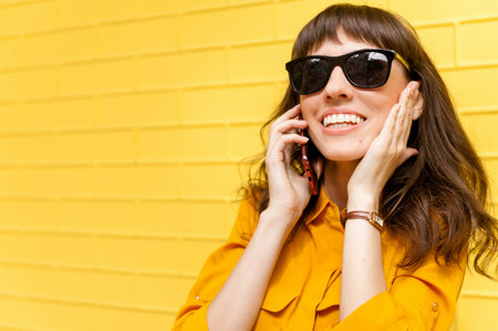 Girl on the phone was told the happy news Girl in yellow shirt against the yellow wall, talking on...