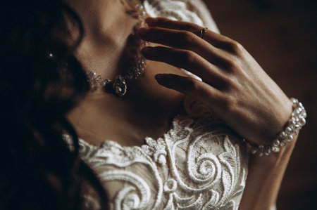 Portrait of the bride. The young bride holds on to the pendant around her neck. The brides face is...