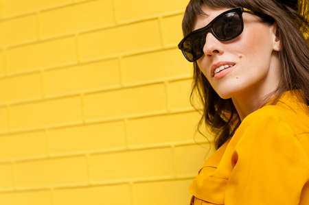 beautiful girl in a yellow shirt against the yellow wall. There is an empty space for inscription and textの写真素材