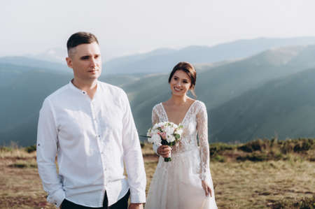 The first meeting of the newlyweds at sunset. Location in the mountainsの写真素材