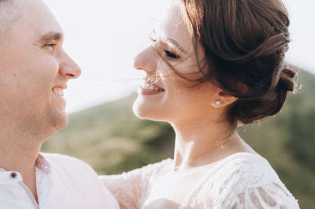 Beautiful fabulous happy bride and stylish groom posing on the background of the sunny stunning mountainsの写真素材