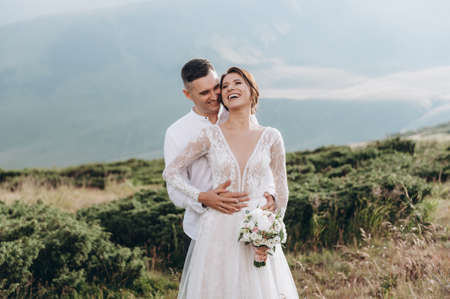 Happy newlyweds smiling, embracing, posing in the mountansの写真素材