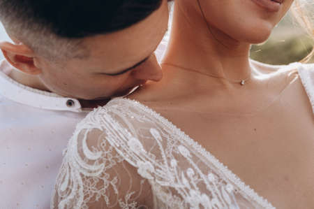 The groom kisses the bride on the shoulder. Sensual portrait of young elegant just married pairの写真素材