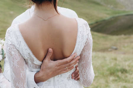 The groom hugs the bride. The bride stands with her backの写真素材