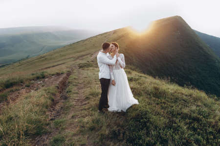 newlyweds kissing in the mountains. Wedding in the mountains at sunsetの写真素材