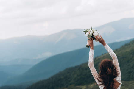 the bride is preparing to throw the bouquet. Bride in the mountainsの写真素材