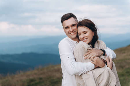 Newlyweds cuddle against the backdrop of the mountainsの写真素材