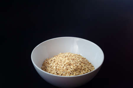 beautiful grains of oatmeal in a white dish on a background with a place for textの写真素材