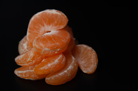 Mandarin slices on a black background with a place for inscription. close-upの写真素材
