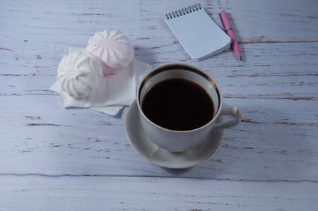 a large cup of coffee and marshmallow stands against the background of a light treeの写真素材