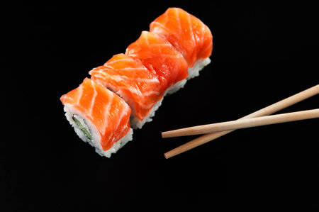 Sushi with red fish on a black background with bamboo sticks