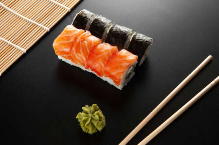 sushi on a black background. Sushi California alongside bamboo sticks and wasabi.の写真素材