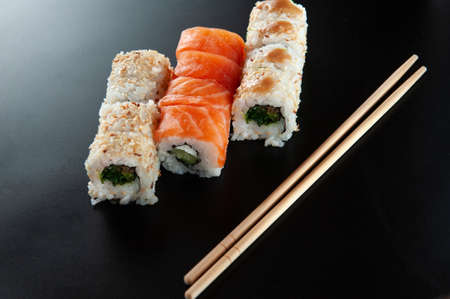 sushi on a dark glossy background near bamboo sticks.の写真素材
