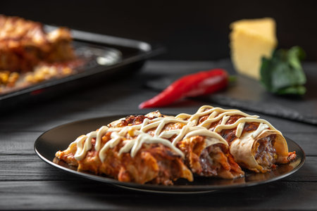The traditional cuisine of Latino Americans Italians and Mexicans. Enchiladas on a black plate
