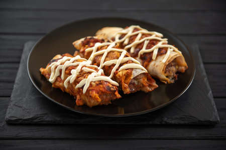 The traditional food of Latino-Americans is encheladas. Pita stuffed with meat and vegetables. On a dark backgroundの写真素材