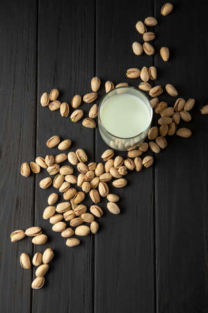 A glass of pistachio milk on a black background. top view. vertical frame. Useful drink for a healthy diet. Pistachio milk contains B vitamins, vitamin K, vitamin A.の写真素材