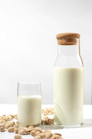 Pistachio milk the glass next to bottle of milk and pistachios. vertical frameの写真素材