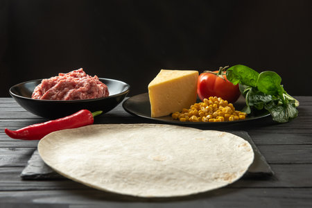 The ingredients for the traditional Latino American dish enchiladas are arranged on a dark background top view. Enchiladas are a traditional Mexican and South American cuisineの写真素材