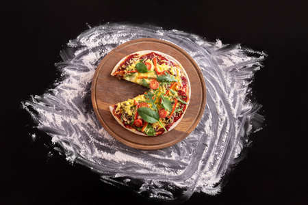 Pizza without one piece on a wooden board on a black backgroundの写真素材