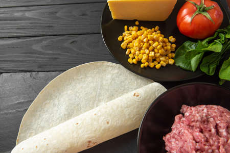 The ingredients for the traditional Latino American dish enchiladas are arranged on a dark background top view. Enchiladas are a traditional Mexican and South American cuisineの写真素材