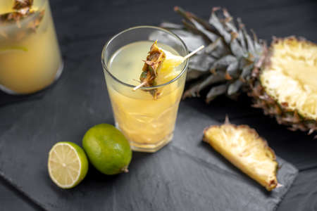 Fruit and pineapple lemonade drink on black background with iceの写真素材