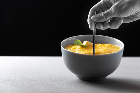 A traditional Italian dish is polenta. Plate gray with corn porridge polenta with a piece of oil on...