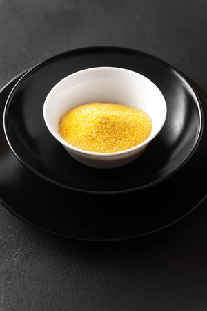 porridge polenta on a black plate on a dark background. Dry porridge. vertical card