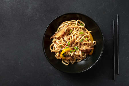 Asian noodles in a bowl on a dark background.Vegetarian noodles, vegetable noodles Hakka Noodles or Chow Mein in a black bowl on a dark background.の写真素材