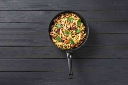 Homemade Italian fettuccini or alfredo pasta, also called Funghi Porcini cooked in a cast iron skillet with mushrooms and cream sauce. Homemade Italian fettuccine pasta with mushrooms and cream sauce - Fettuccine al Funghi Porcini. Traditional Italian cuisine. Served on a dark table with a rustic wooden background. Close-up. A traditional Italian and Roman dish, fettuccini pasta with spinach and mushrooms in a pan. Roman pastaの写真素材