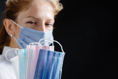 the doctor holds several masks of different colors in his hands. A nurse wearing a mask and medical...