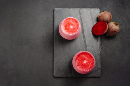 Two cups of hot beet coffee latte on a dark background. A trendy, healthy drink. An alternative to...