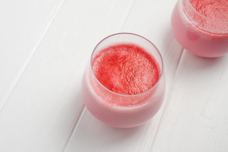 A cup of hot beet coffee latte on a light wooden background. A trendy, healthy drink. Two cups of...