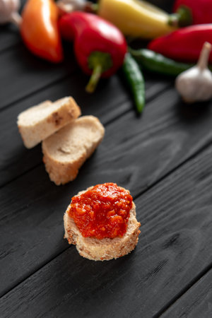 Toast with ajika, on a wooden dark background. The ingredients are side by side.