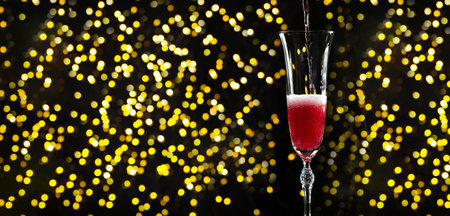 A glass of champagne in front of the garland. New Year and Christmas mood yellow circles bokeh. Copy space for textの写真素材