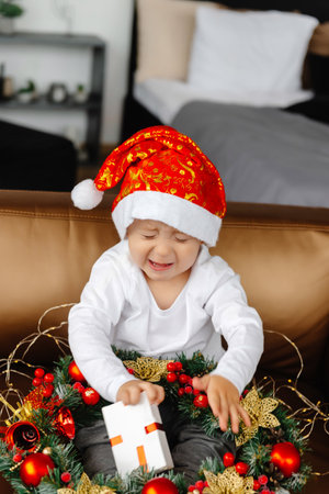 Christmas child opens a gift, happy boy tries to open a box of gifts. The boy tries to open the box of gifts, but it does not workの写真素材