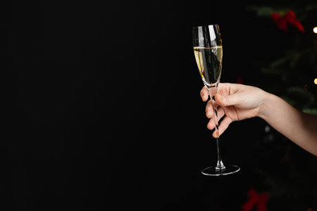 A womans hand with a glass of champagne on a dark background.の写真素材