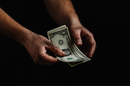The dirty hands of a homeless man, a poor man holding not much money, dollars. The concept of helping homeless and underprivileged peopleの写真素材
