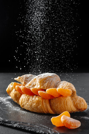 Sweet croissant sandwich with powdered sugar on a dark background. Baking and bakery conceptの写真素材