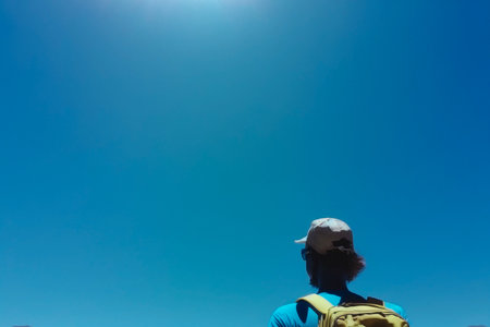 A male traveler with a bright yellow backpack against a blue sky. Blank space for text. The concept of freedom and leisure advertising, summer vacations.の素材