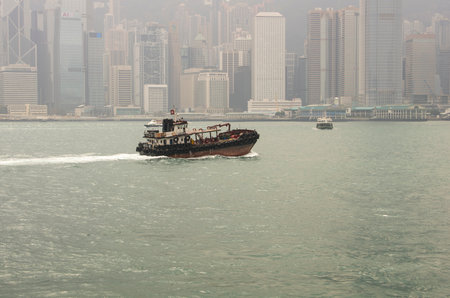 HONG KONG - FEBRUARY 25: A boat in front of the Hong Kong central district on February 25, 2013 in Hong Kong. Hong Kong is an international financial centre that has 112 buildings that stand taller than 180 metresのeditorial素材