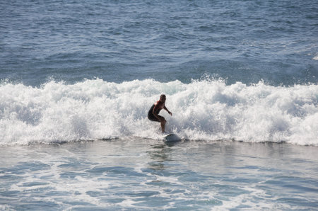 GRAN CANARIA, CANARY ISLANDS - JANUARY 05, 2014: Unidentified man surfing on a large wave on Playa del Ingles on the coast of Atlantic ocean, Gran Canaria, Canary islands, Spainのeditorial素材