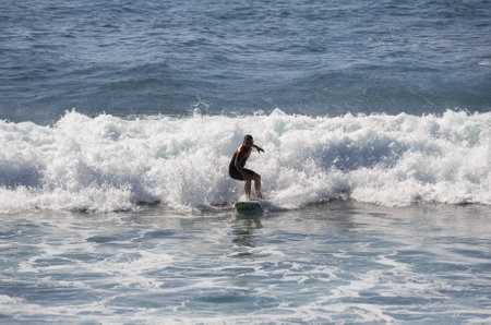 GRAN CANARIA, CANARY ISLANDS - JANUARY 05, 2014: Unidentified man surfing on a large wave on Playa del Ingles on the coast of Atlantic ocean, Gran Canaria, Canary islands, Spainのeditorial素材