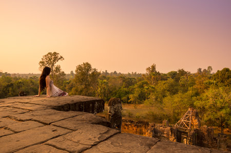ANGKOR WAT, CAMBODIA - JANUARY 28, 2015: Young beautiful woman watching sunset at the top of Phnom Bakheng at Angkor, Cambodiaのeditorial素材