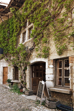PEROUGES, FRANCE - 29 APRIL, 2015: Old stone house at medieval village Perouges in France with green lianas climbing up the wallのeditorial素材