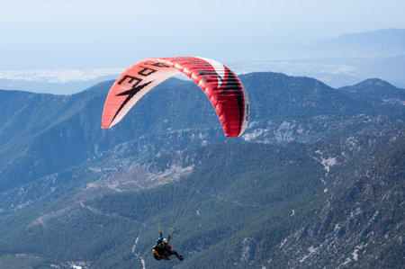 KEMER, TURKEY - OCTOBER 22, 2017: Paraglider flying over mountains near Kemer, a seaside resort on the Turkish Riviera in Antalya Province, Turkeyのeditorial素材