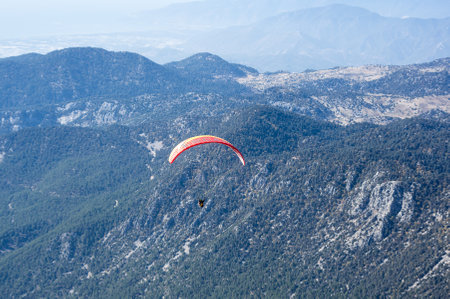 KEMER, TURKEY - OCTOBER 22, 2017: Paraglider flying over mountains near Kemer, a seaside resort on the Turkish Riviera in Antalya Province, Turkeyのeditorial素材