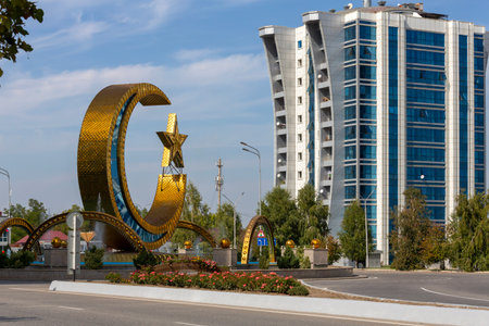 ARGUN, CHECHEN REPUBLIC, RUSSIA - SEPTEMBER 23, 2023: A large metal structure of crescent moon with a star against modern house, in the center of the city of Argunのeditorial素材
